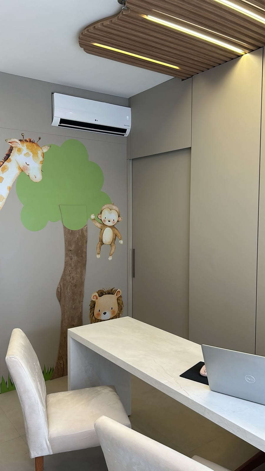 Consultório com mesa de atendimento e murais de girafa e leão